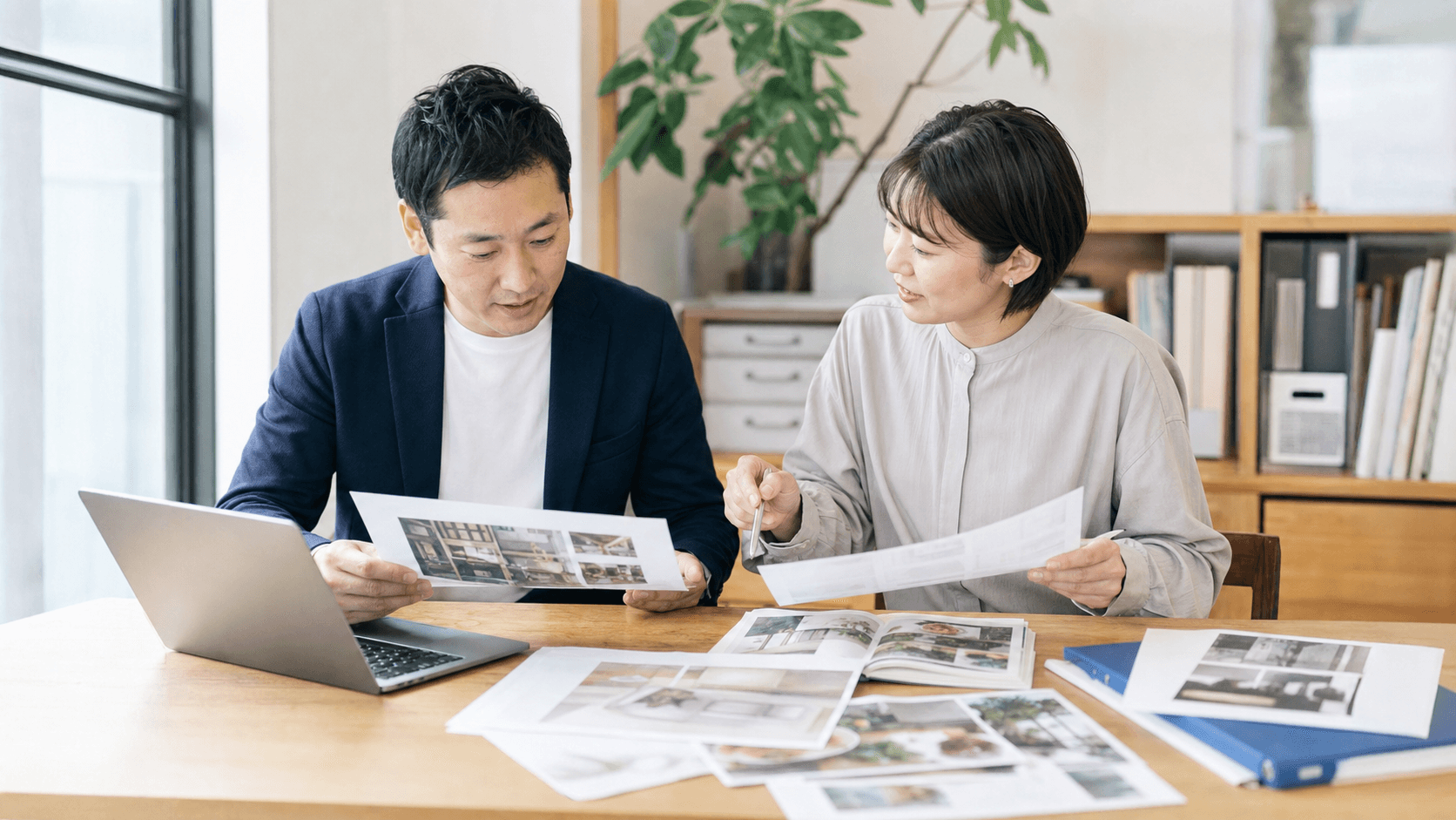 徳島の中小企業の担当者が、ノートPCの横に商品写真や印刷資料を広げ、ホームページ公開前の更新準備を打ち合わせている様子